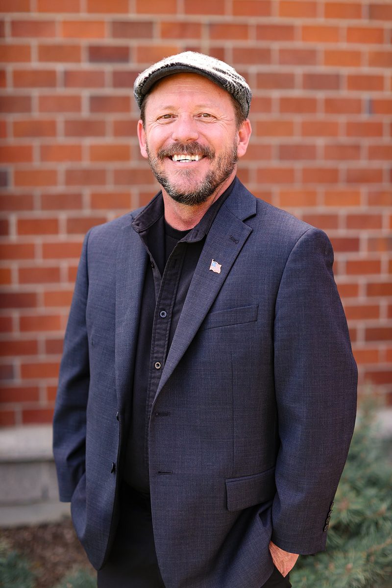 Paul Burke standing in front of a brick wall